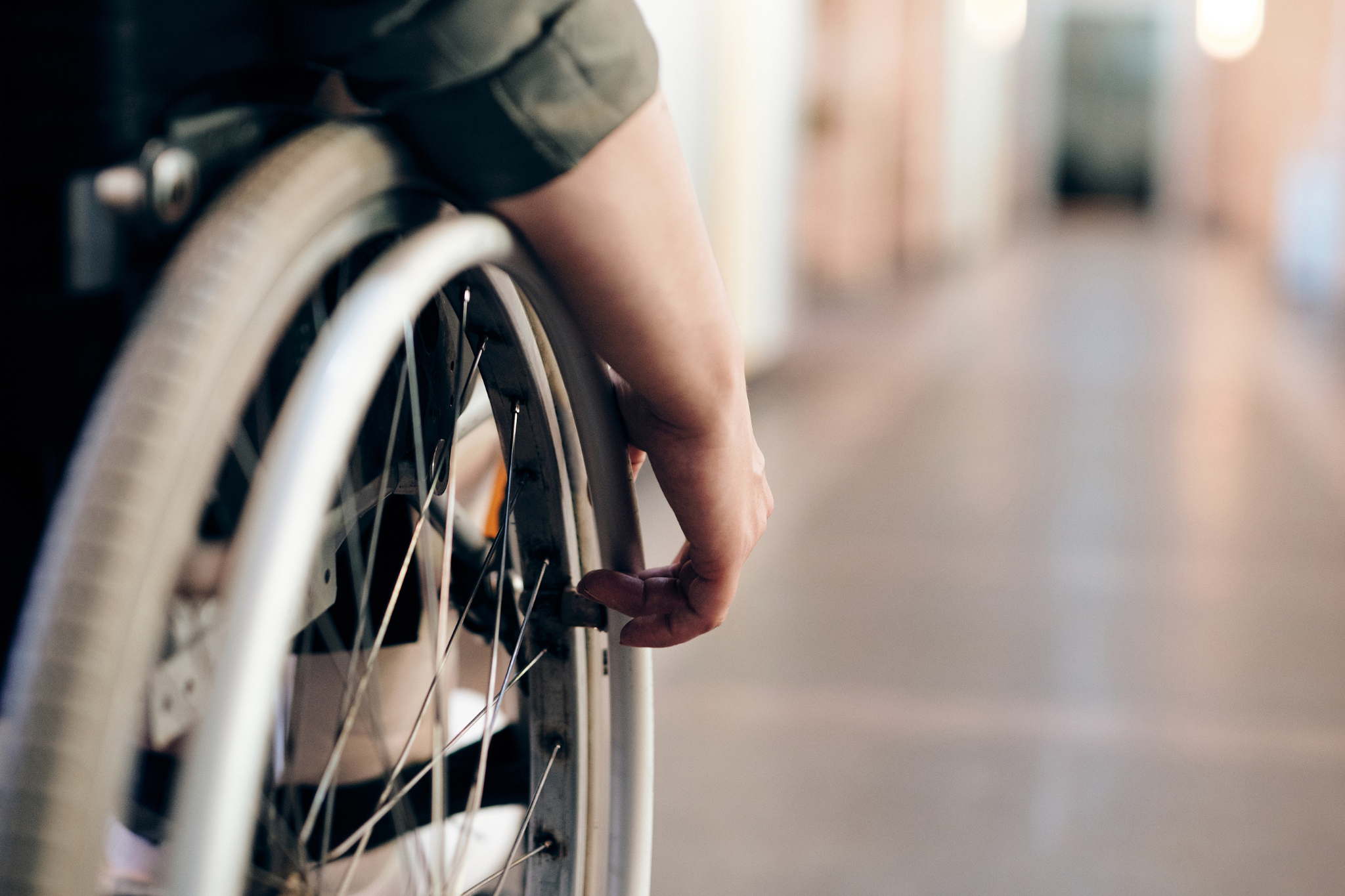 Pyörätuolin käyttäjän käsi pitää kiinni pyörätuolin kelasta.