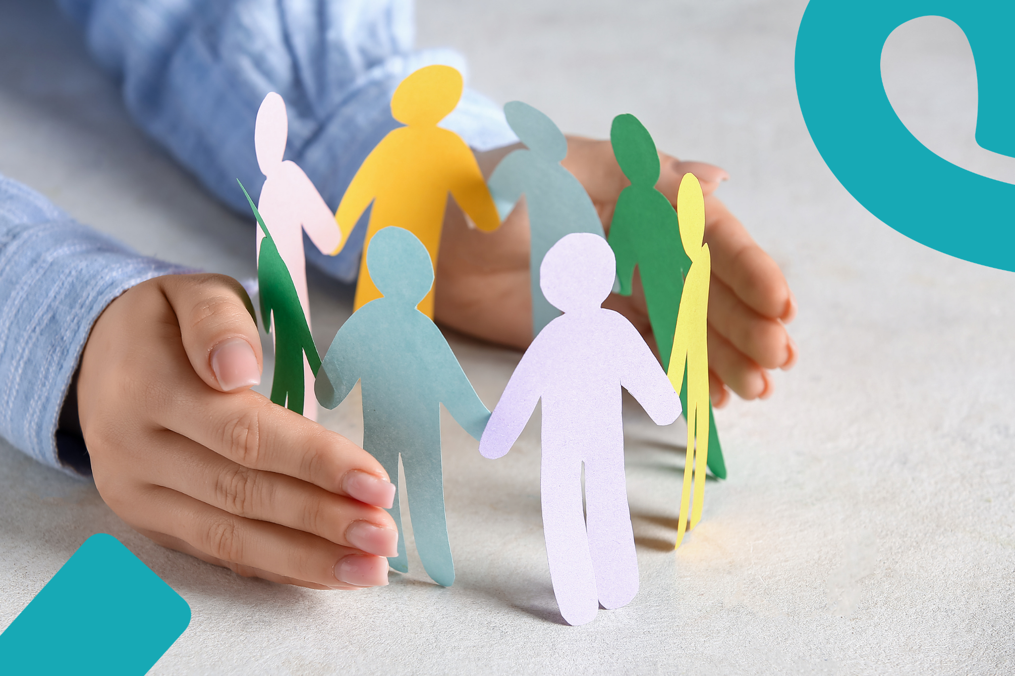 Käsien välissä erilaisia paperihahmoja ympyrämuodostelmassa.